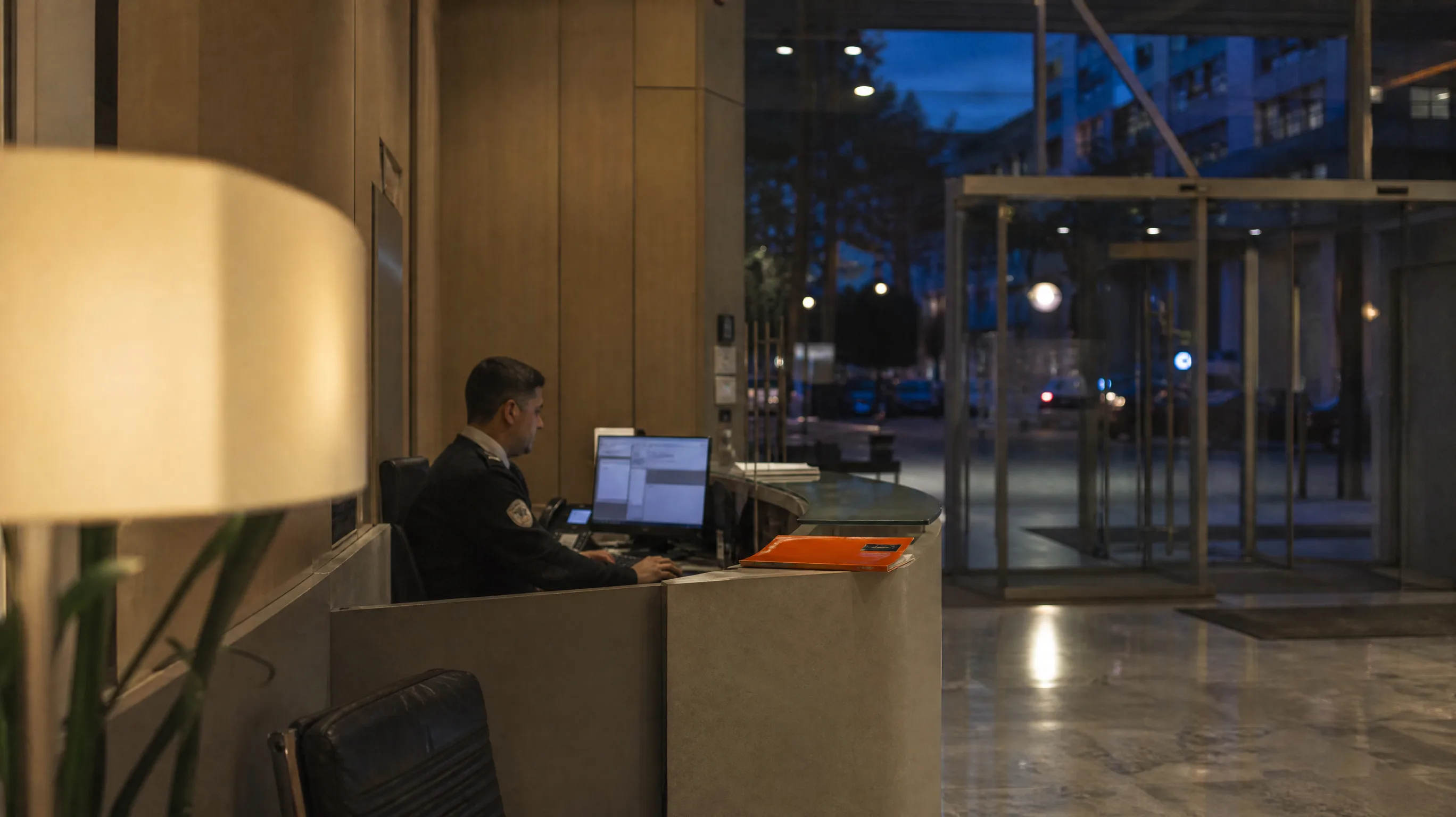 Portaria de um edifício de escritórios ao fim do dia, com o posto de vigilância iluminado
